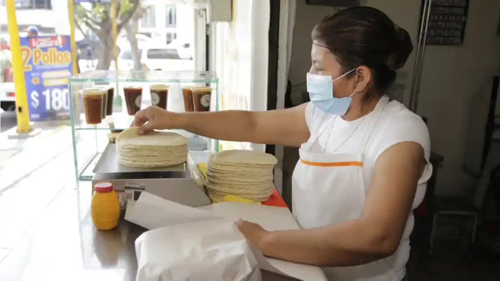 Mujer pesando tortillas en una báscula.