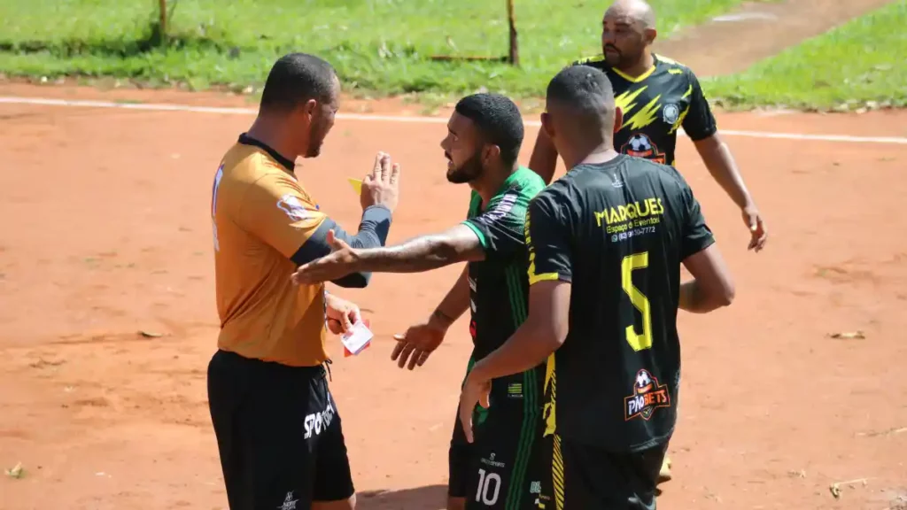 Árbitro mostrándole una tarjeta amarilla a un jugador durante un partido de fútbol.